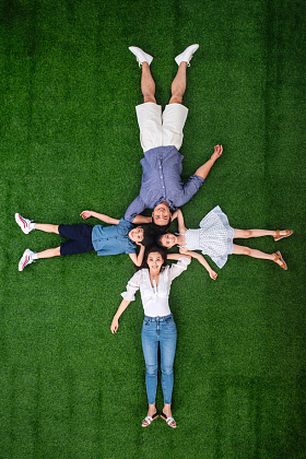 幸福的一家四口头挨着头躺在草地上