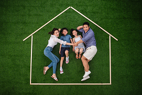 幸福的四口之家躺在草地上的房子轮廓