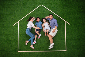 幸福的四口之家躺在草地上的房子轮廓