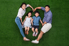 幸福的四口之家躺在草地上组成心形