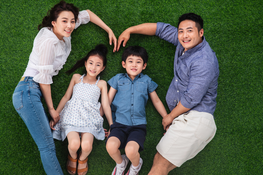 幸福的四口之家躺在草地上组成心形