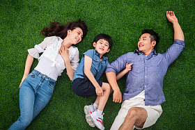 快乐的一家三口躺在草地上嬉戏