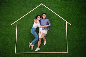 青年伴侣躺在草地上的房子轮廓