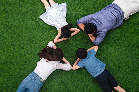 幸福的一家四口面对面趴在草地上