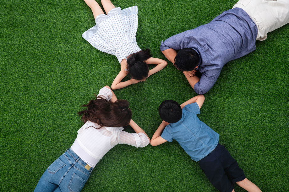 幸福的一家四口面对面趴在草地上