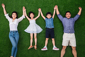 幸福的一家四口手牵手躺在草地上