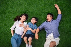 快乐的一家三口躺在草地上嬉戏