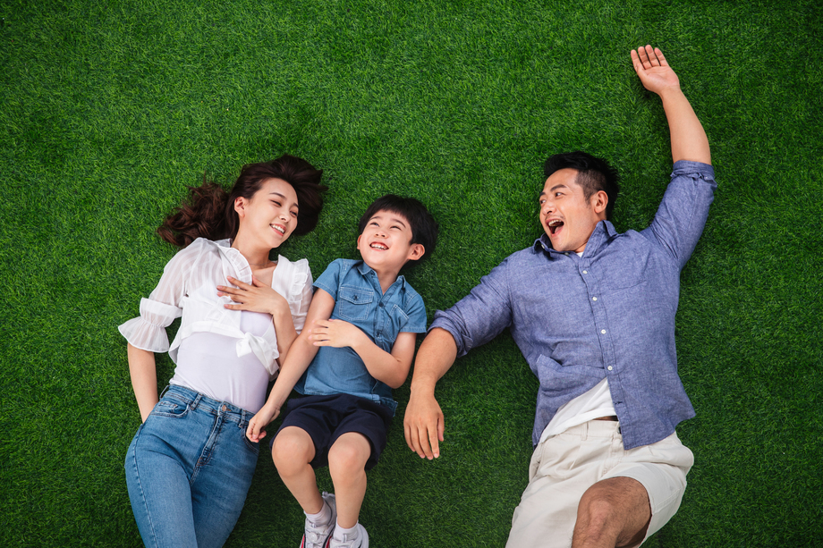 快乐的一家三口躺在草地上嬉戏 快乐的一家三口躺在草地上嬉戏