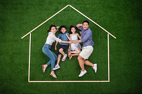 幸福的四口之家躺在草地上的房子轮廓