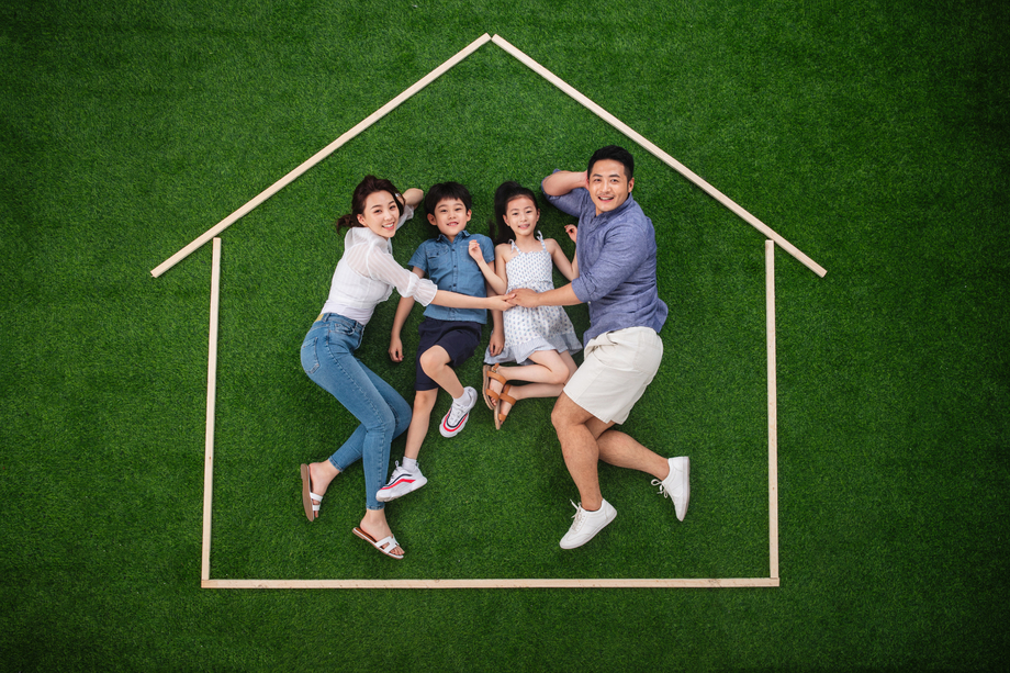 幸福的四口之家躺在草地上的房子轮廓