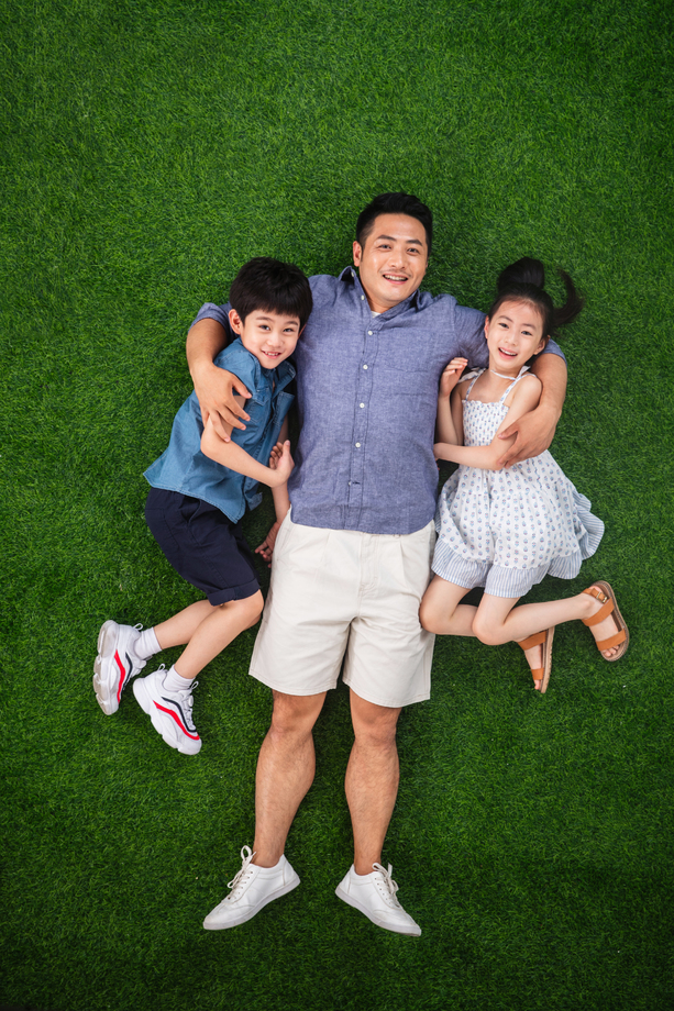 父亲搂着儿子和女儿躺在草地上 父亲搂着儿子和女儿躺在草地上