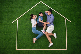 快乐的一家三口躺在草地上的房子轮廓