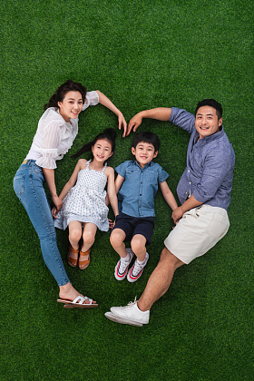 幸福的四口之家躺在草地上组成心形