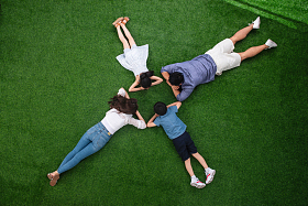 幸福的一家四口面对面趴在草地上