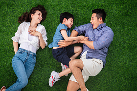 快乐的一家三口躺在草地上嬉戏