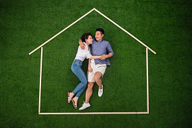 青年伴侣躺在草地上的房子轮廓