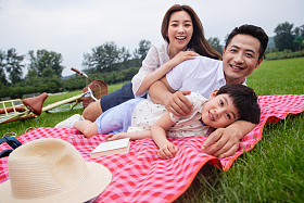 幸福的一家三口侧卧在野餐垫上
