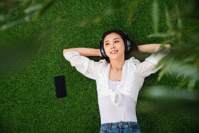 躺在草地上听音乐的青年女人