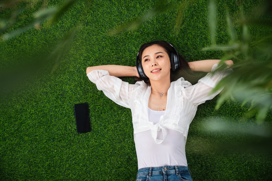 躺在草地上听音乐的青年女人
