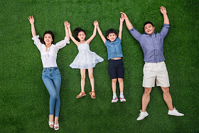 幸福的一家四口手牵手躺在草地上