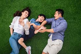 快乐的一家三口躺在草地上嬉戏