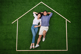 青年伴侣躺在草地上的房子轮廓