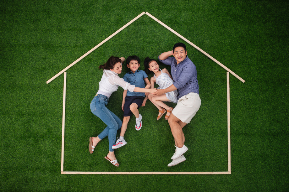 快乐的一家四口躺在草地上的房子轮廓