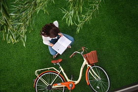 坐在草地上看书的青年女人图片