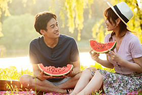 坐在草地上吃西瓜的幸福情侣照片