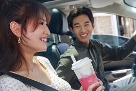 青年伴侣坐在汽车里喝饮料图片