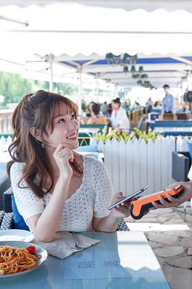 年轻女人在餐厅用手机付款照片