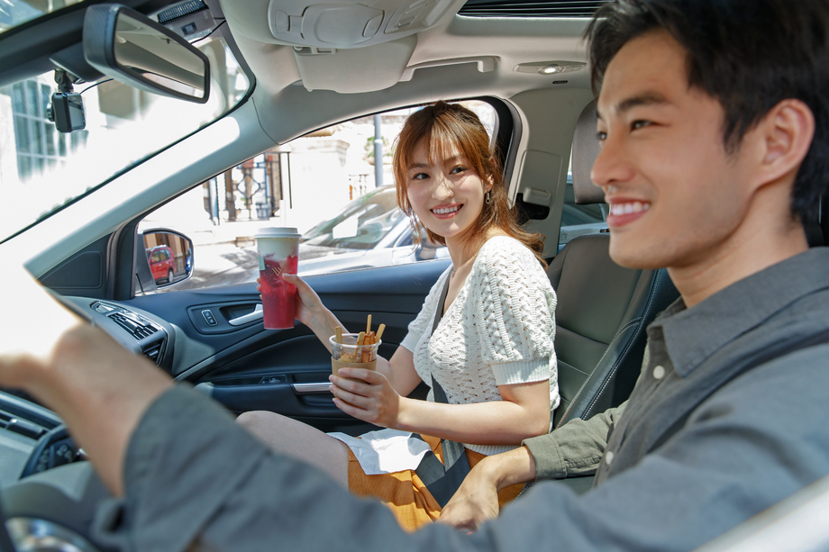 拿着饮料坐在汽车里快乐情侣 拿着饮料坐在汽车里快乐情侣