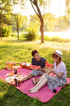 青年情侣坐在公园里吃西瓜照片