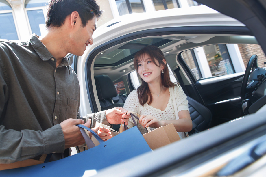 拿着购物袋站在汽车旁的幸福情侣 拿着购物袋站在汽车旁的幸福情侣