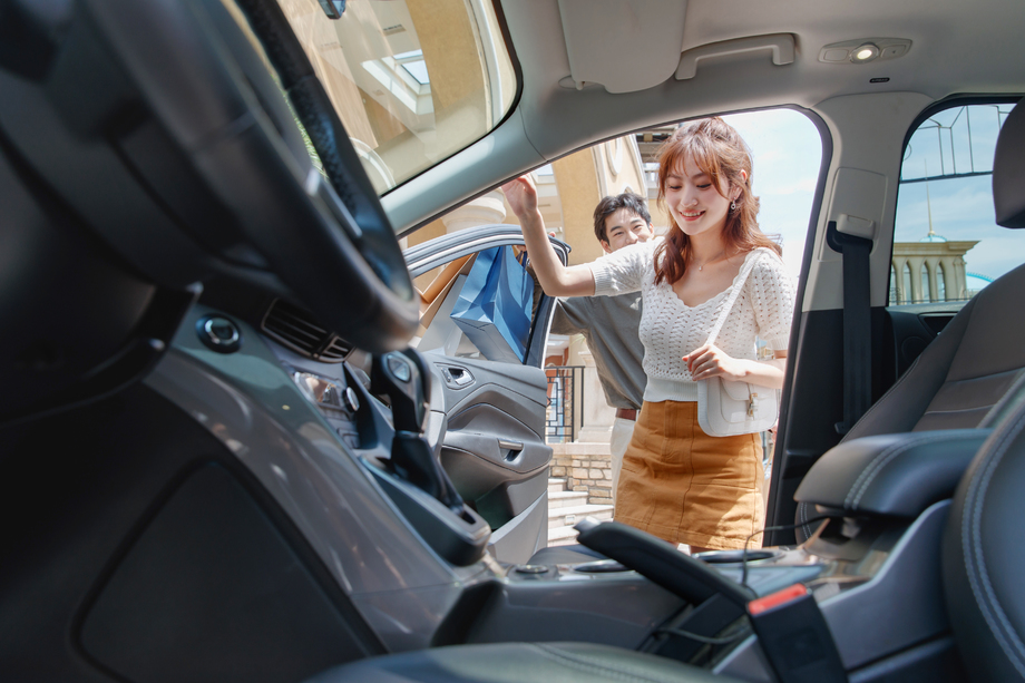 拿着购物袋站在汽车旁的幸福情侣 拿着购物袋站在汽车旁的幸福情侣