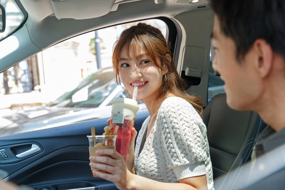 青年伴侣坐在汽车里喝饮料图片