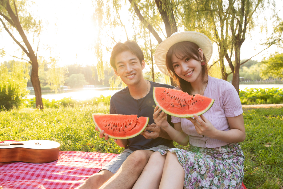 青年情侣坐在公园里吃西瓜 青年情侣坐在公园里吃西瓜