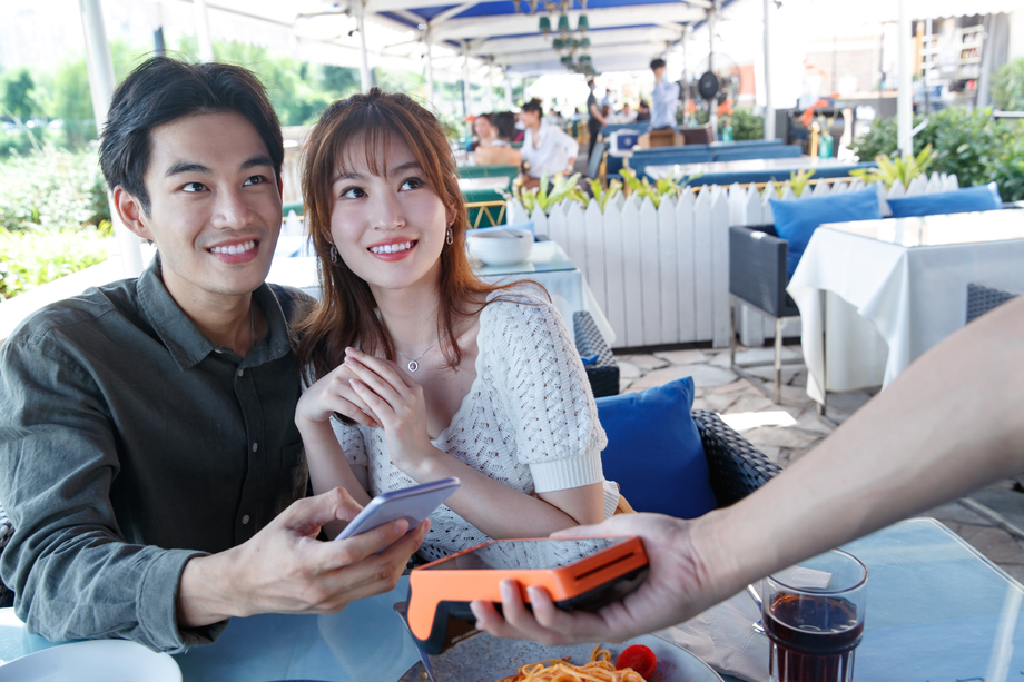 年轻情侣在餐厅用手机付款 年轻情侣在餐厅用手机付款