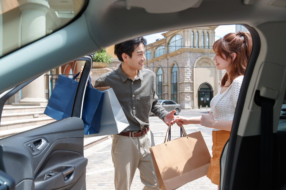 拿着购物袋站在汽车旁的幸福情侣 拿着购物袋站在汽车旁的幸福情侣