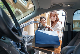 拿着购物袋站在汽车旁的幸福情侣