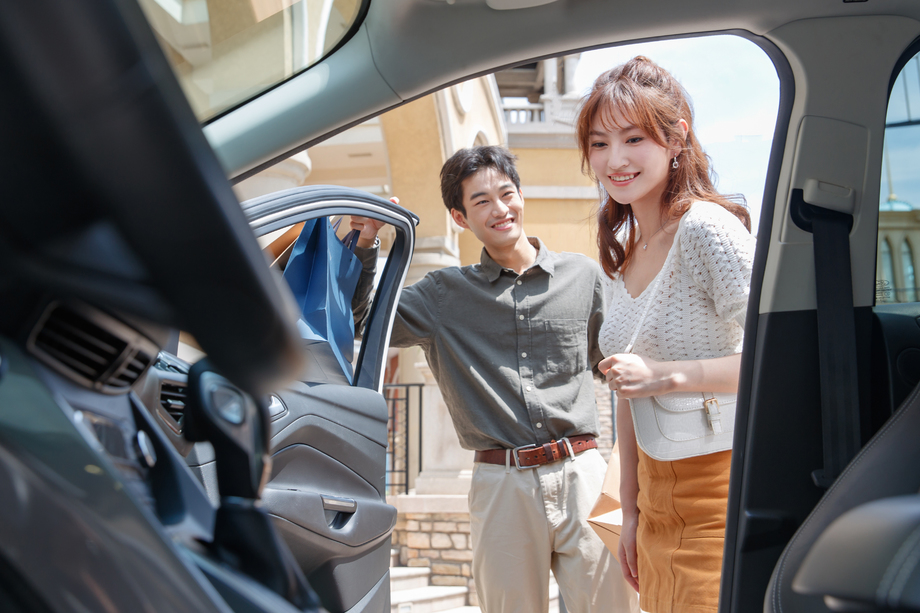 拿着购物袋站在汽车旁的幸福情侣 拿着购物袋站在汽车旁的幸福情侣