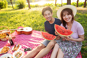 青年情侣坐在公园里吃西瓜