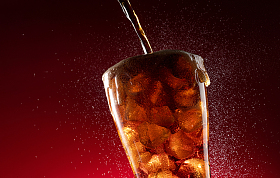可乐倒入装满冰块的杯中照片