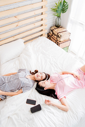 躺在床上敷面膜的年轻闺蜜