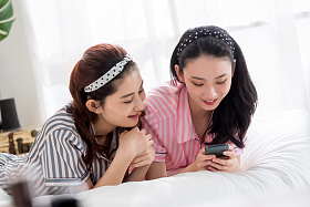快乐闺蜜趴在床上玩手机照片