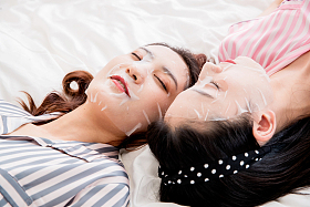 年轻闺蜜躺在床上敷面膜图片