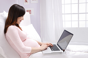 孕妇坐在床上看电脑照片