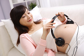 孕妇把耳机放在肚子上照片