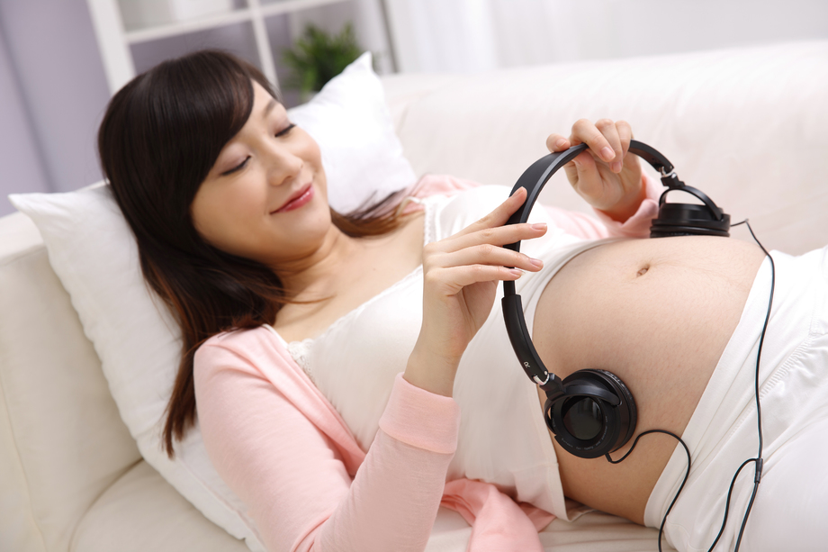 孕妇把耳机放在肚子上照片