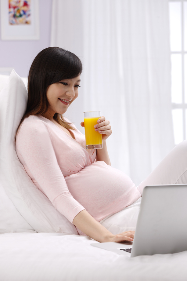孕妇坐在床上看电脑